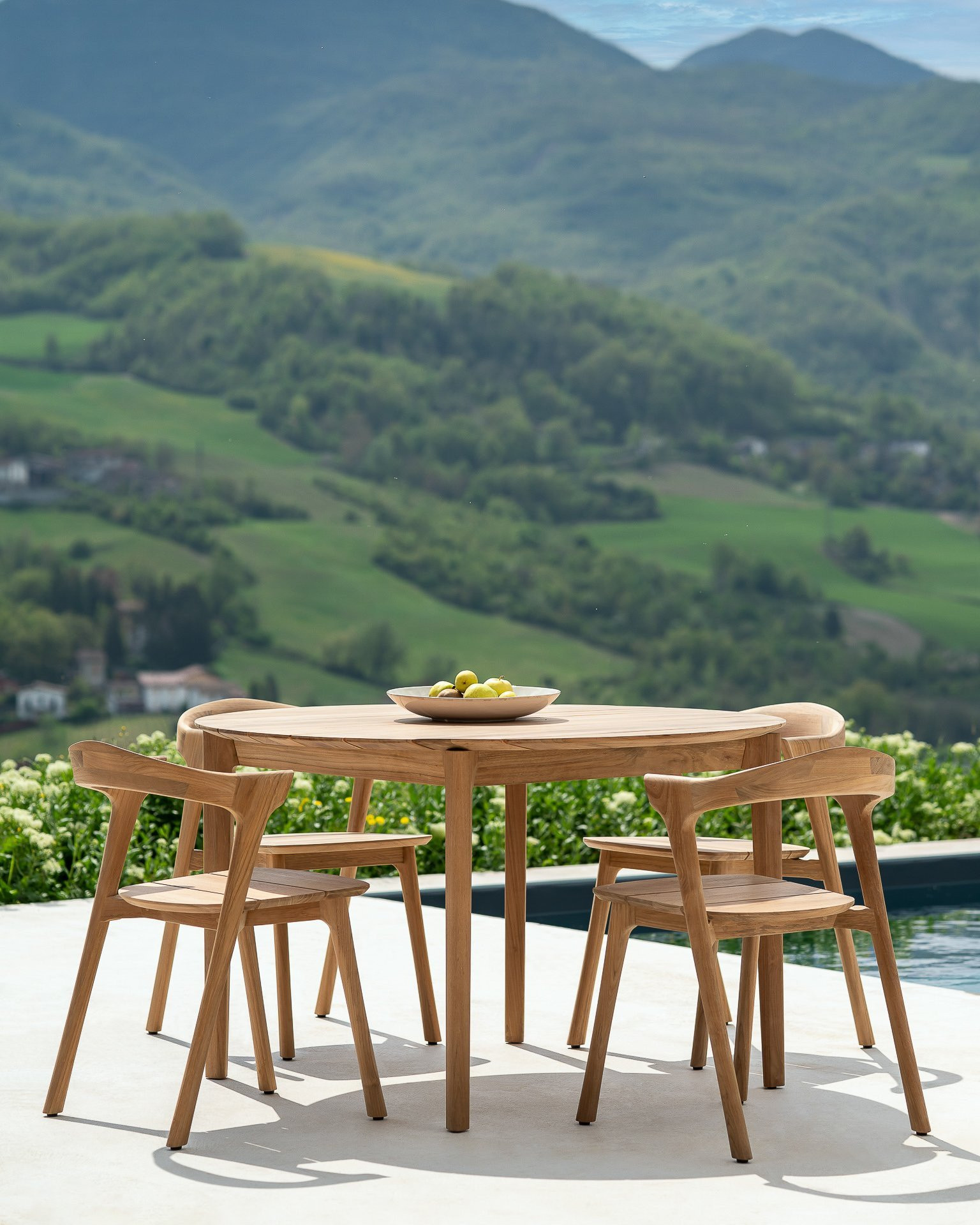 Ethnicraft Teak Bok Outdoor Dining Set auf einer Terrasse mit Bergpanorama und Pool